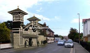 A 'then and now' overlay of the Victorian Swiss Gardens entrance gateway superimposed on the modern Victoria Road street.